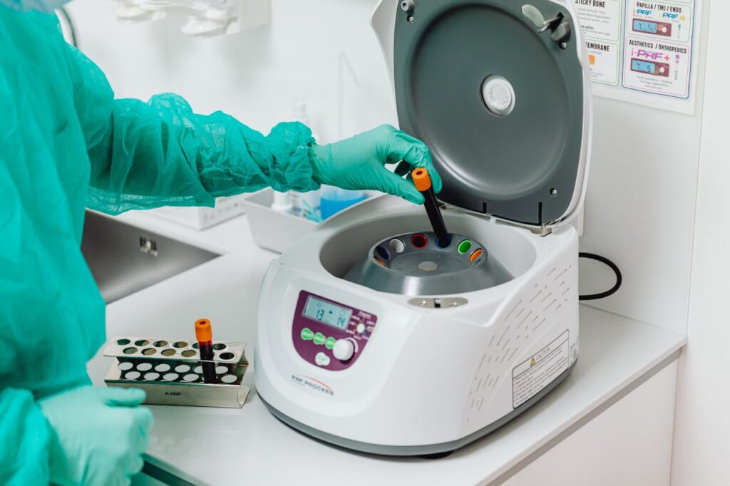 A healthcare professional operates a centrifuge machine in a laboratory, ensuring sterile medical procedures.